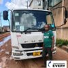 Customer in Zambia standing in front of a MITSUBISHI FIGHTER truck while holding an EVERY sign