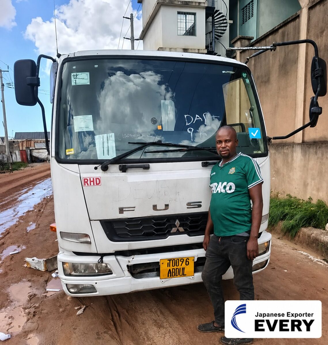 Customer in Zambia standing in front of a MITSUBISHI FIGHTER truck while holding an EVERY sign